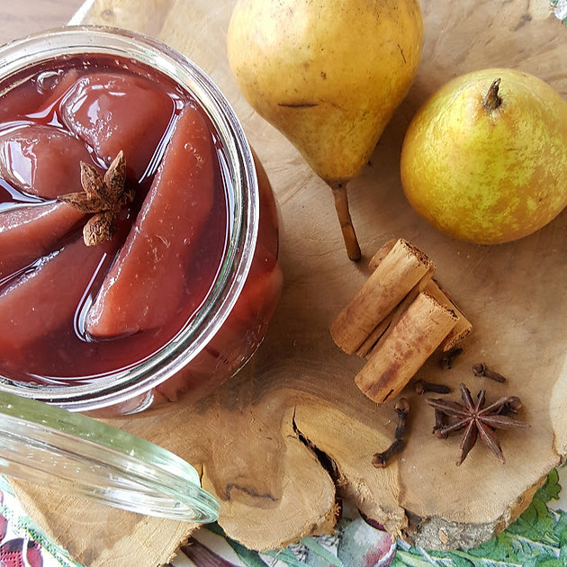 Weekpot met peren op siroop naast verse peren, kaneel en kruidnagel, warme herfsttinten