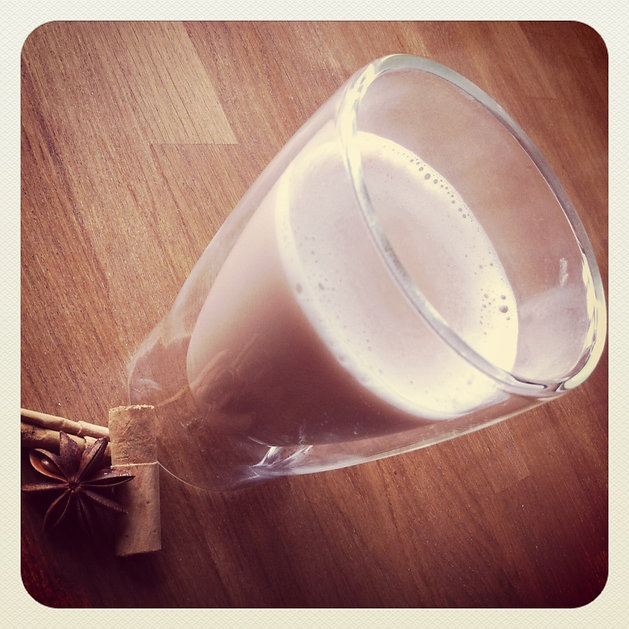 Glas romige drank op houten tafel met steranijs en kaneelstokjes, warme bruintinten, knusse sfeer